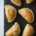 six beef empanadas from above on a black chalk tray